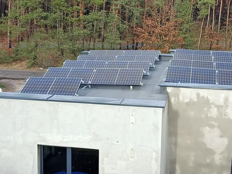 Instalacja fotowoltaiczna na dachu budynku przy lesie