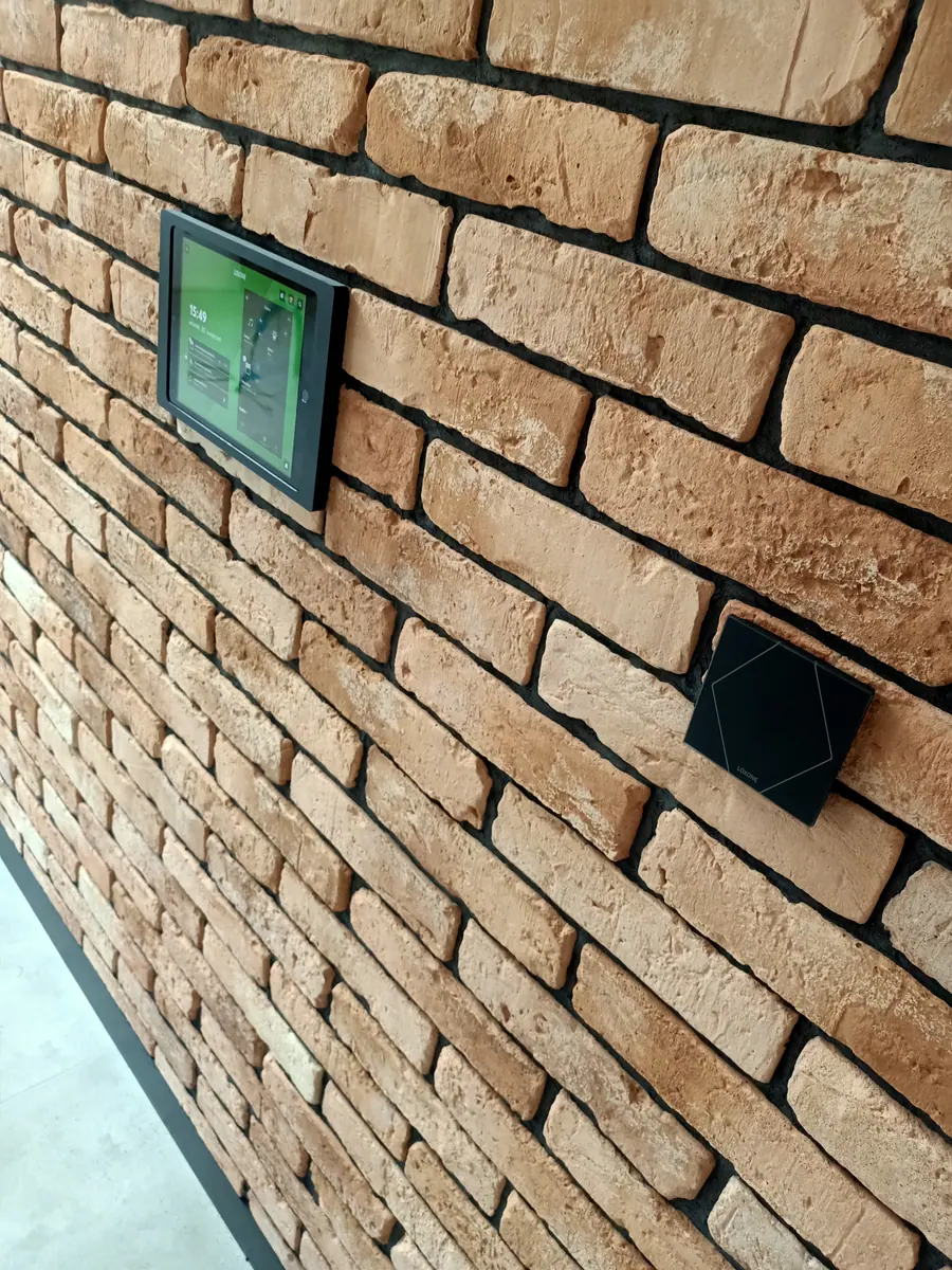 Tablet i przycisk Loxone na ścianie z cegły